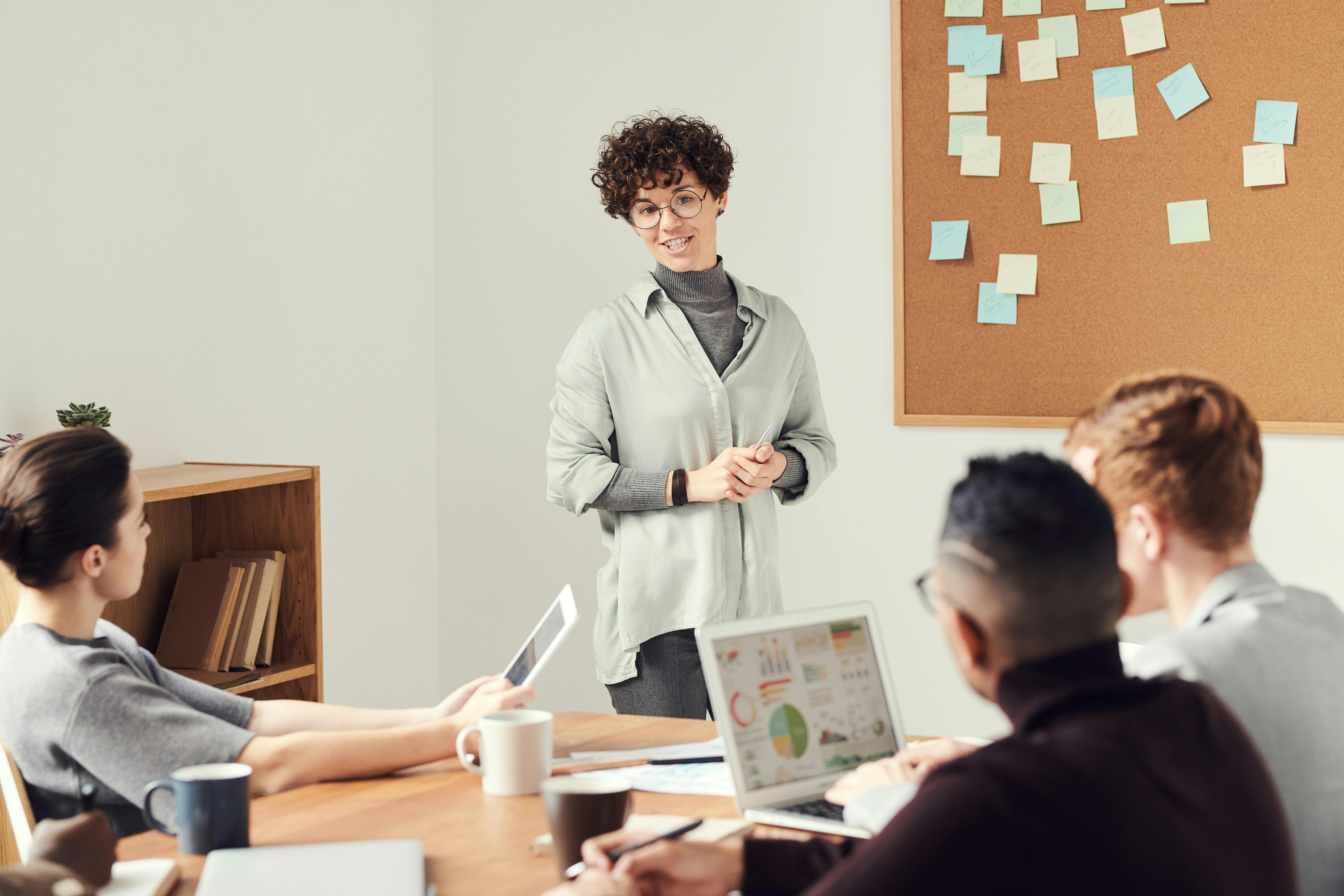 photo of person presenting in front of people in meeting room