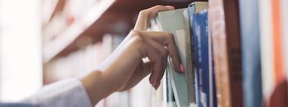 woman grabbing books off a shelf
