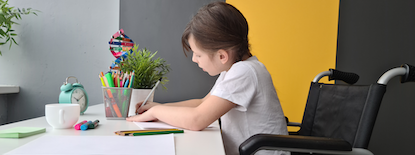 girl in wheelchair at a desk doing work
